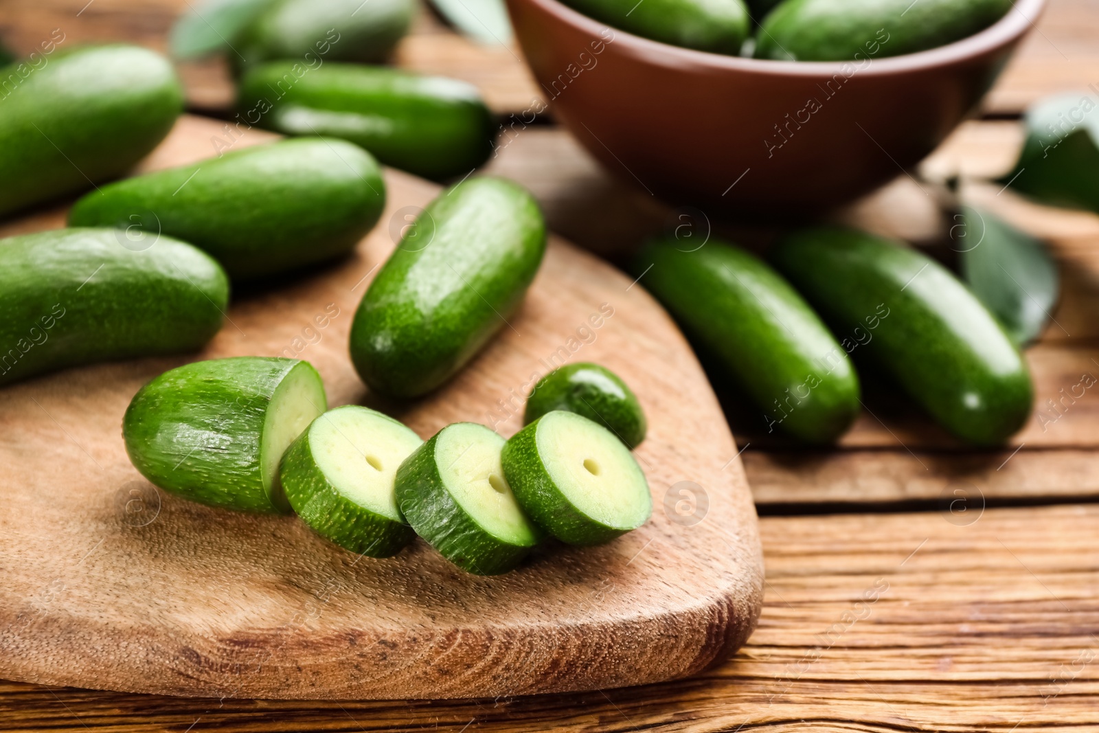 Photo of Fresh seedless avocados with green leaves on wooden table, closeup