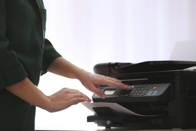 Photo of Employee using modern printer in office, closeup