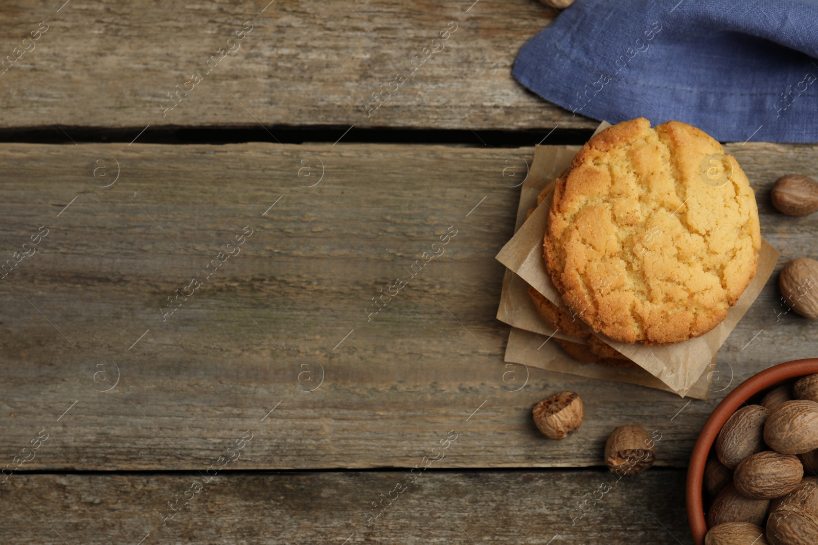 Photo of Tasty cookies and nutmeg seeds on wooden table, flat lay. Space for text