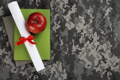 Photo of Books, apple and diploma on camouflage background, top view with space for text. Military education concept