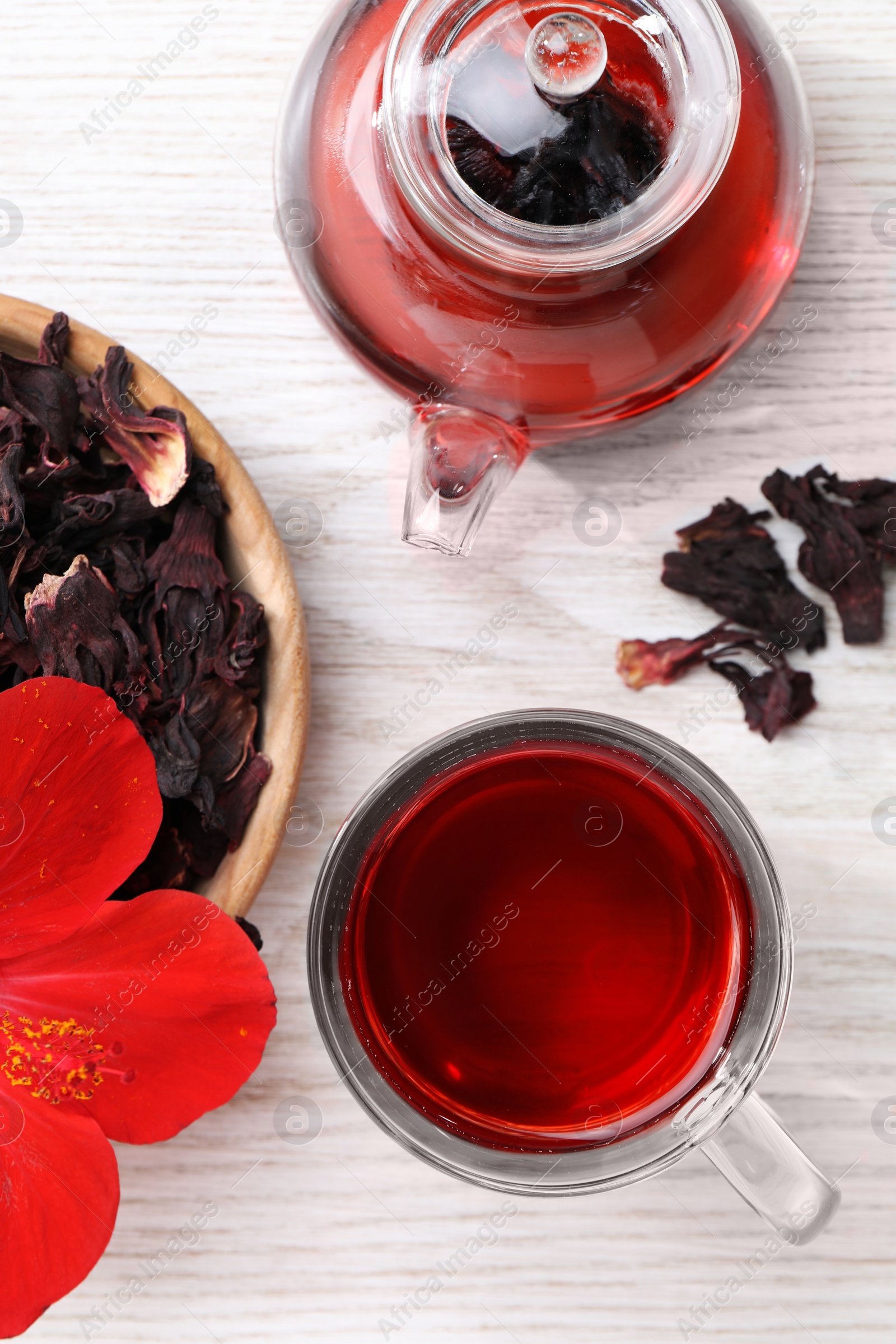 Photo of Delicious hibiscus tea and flowers on white wooden table, flat lay