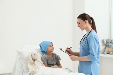 Photo of Childhood cancer. Doctor with clipboard and little patient in hospital