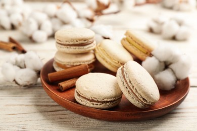 Photo of Delicious macarons and cotton flowers on white wooden table