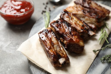 Photo of Delicious grilled ribs served on grey table, closeup
