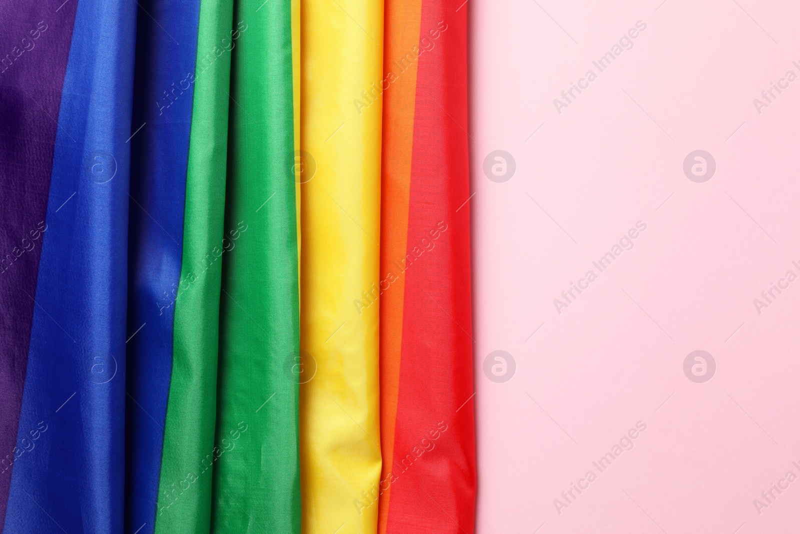 Photo of Rainbow LGBT flag on pink background, top view. Space for text