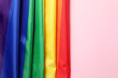 Photo of Rainbow LGBT flag on pink background, top view. Space for text