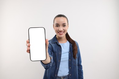 Photo of Young woman showing smartphone in hand on white background