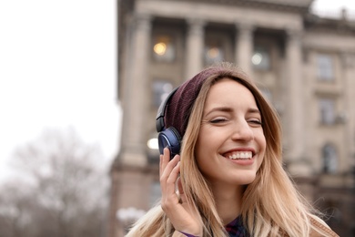 Young woman with headphones listening to music outdoors. Space for text