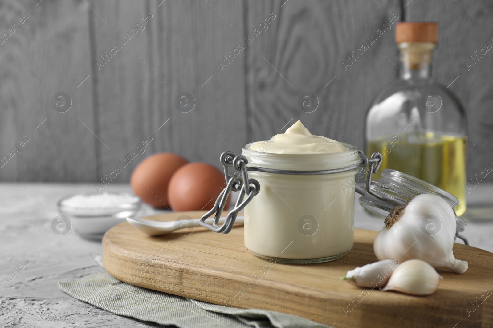 Photo of Tasty mayonnaise in jar and garlic on table, closeup. Space for text