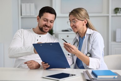 Professional doctor working with patient at white table in hospital