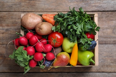 Crate full of different vegetables and fruits on wooden table, top view. Harvesting time
