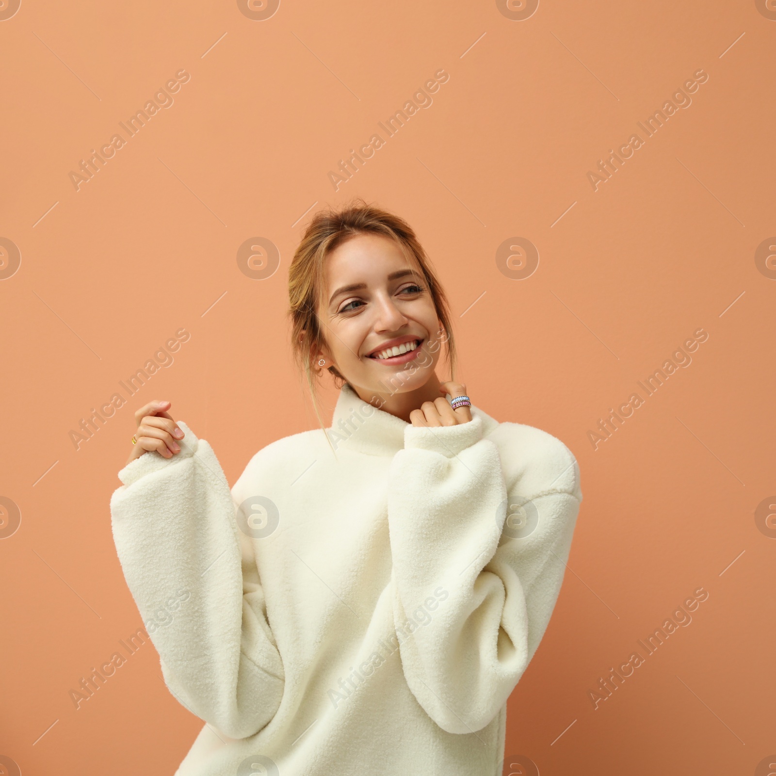 Photo of Beautiful young woman wearing knitted sweater on light brown background