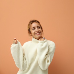 Photo of Beautiful young woman wearing knitted sweater on light brown background