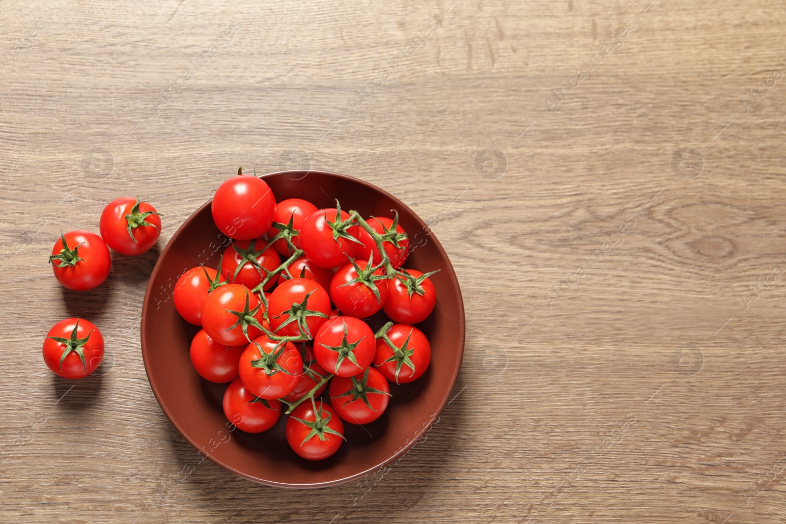 Photo of Plate with fresh cherry tomatoes on wooden background, top view. Space for text