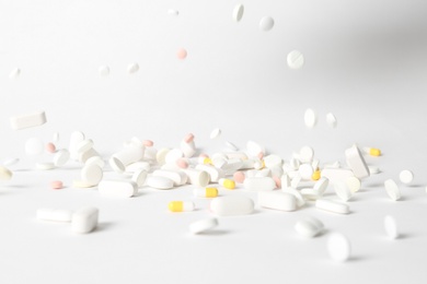 Photo of Different pills falling on table against white background