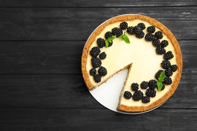 Photo of Delicious cheesecake decorated with blackberries on blue wooden table, top view. Space for text