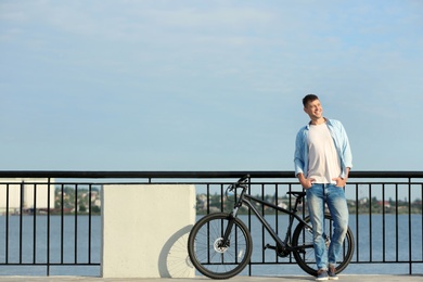 Handsome man with modern bicycle near river