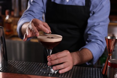 Photo of Bartender preparing Espresso Martini in bar, closeup. Alcohol cocktail