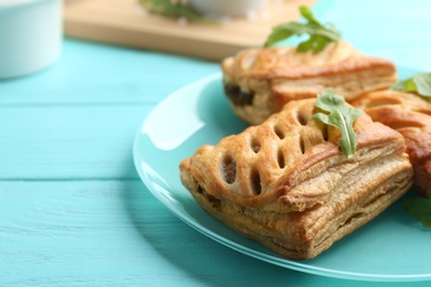 Photo of Fresh delicious puff pastry served on light blue wooden table, closeup