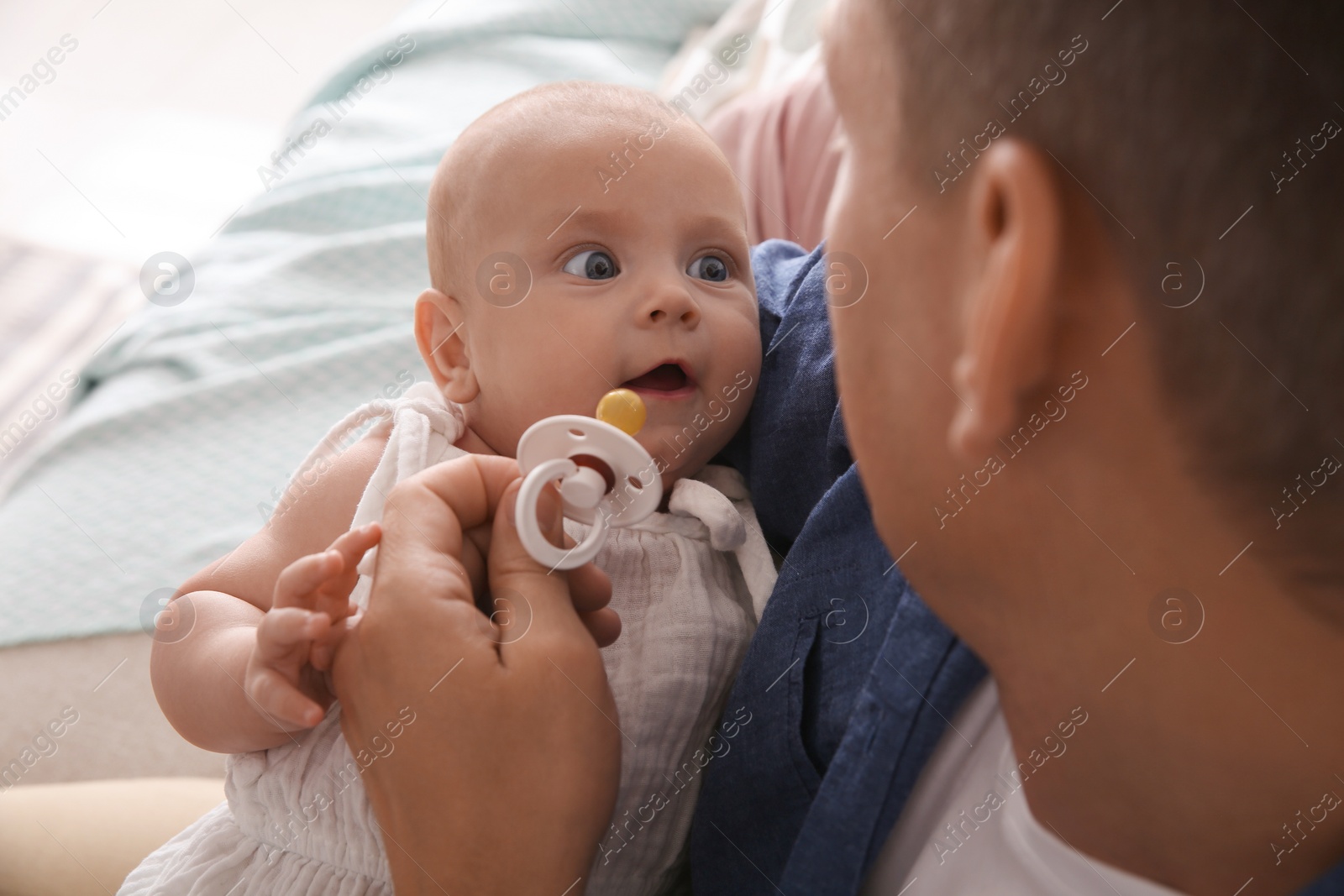 Photo of Father holding his cute little baby with pacifier at home