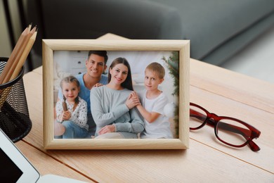 Photo of Framed family photo near laptop on wooden table in office