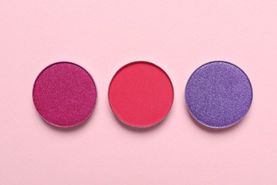 Different beautiful eye shadows on pink background, flat lay