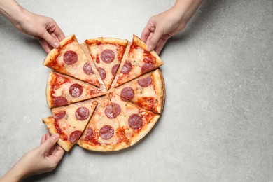 Photo of People taking slices of tasty pepperoni pizza at light grey table, top view