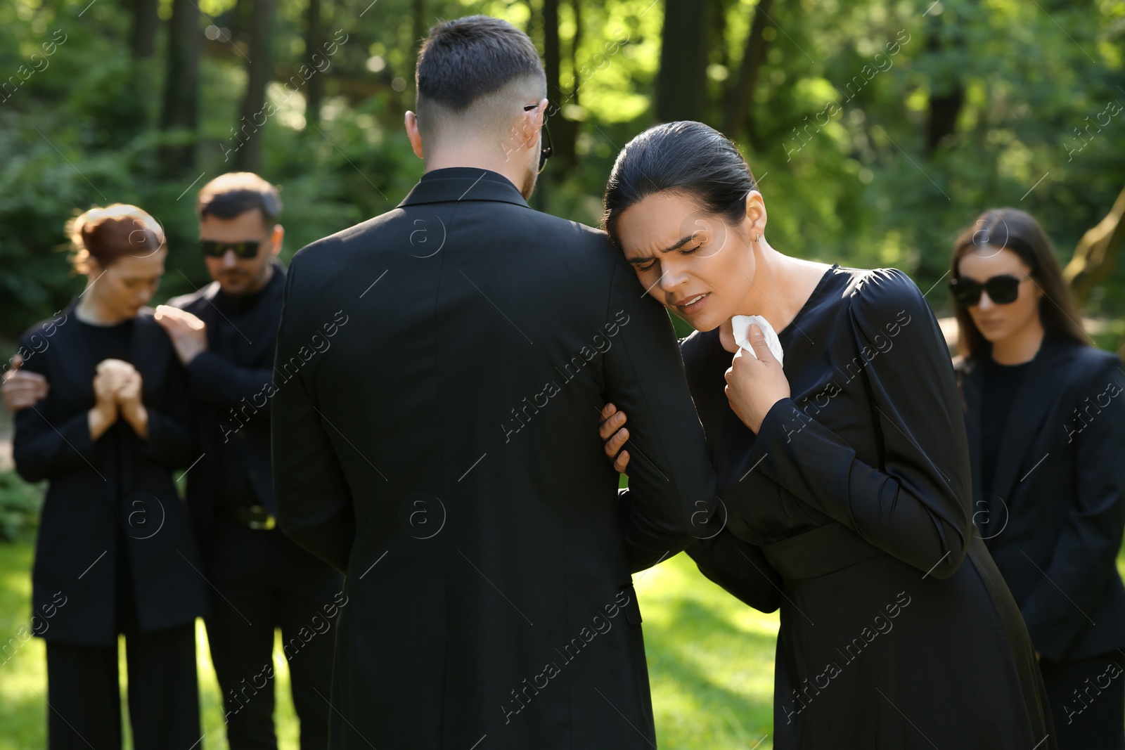 Photo of Sad people in black clothes mourning outdoors. Funeral ceremony