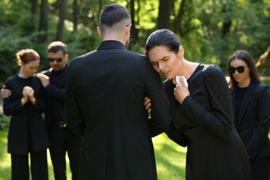 Sad people in black clothes mourning outdoors. Funeral ceremony