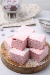 Photo of Tasty marshmallows with powder sugar on white textured table, closeup