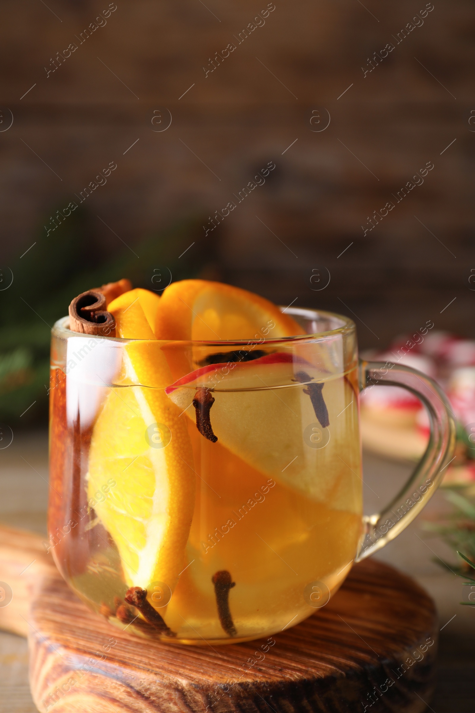 Photo of Aromatic mulled wine on wooden board, closeup