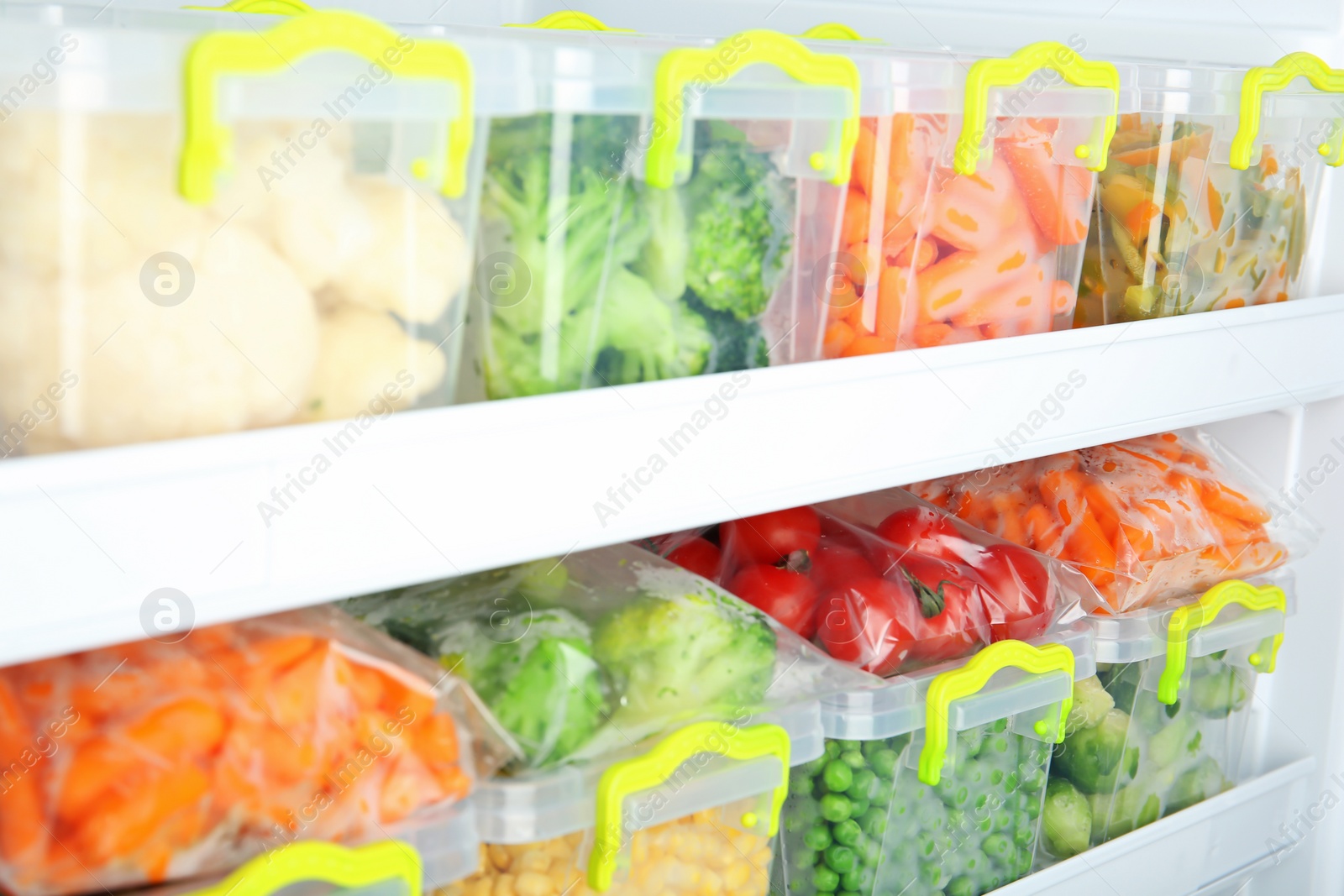 Photo of Containers with deep frozen vegetables in refrigerator