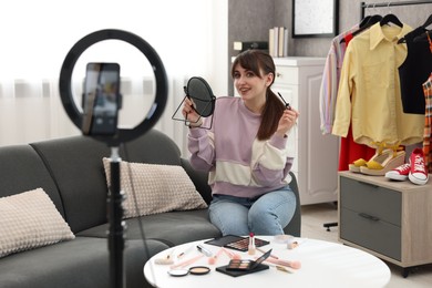 Photo of Smiling beauty blogger recording makeup tutorial at home