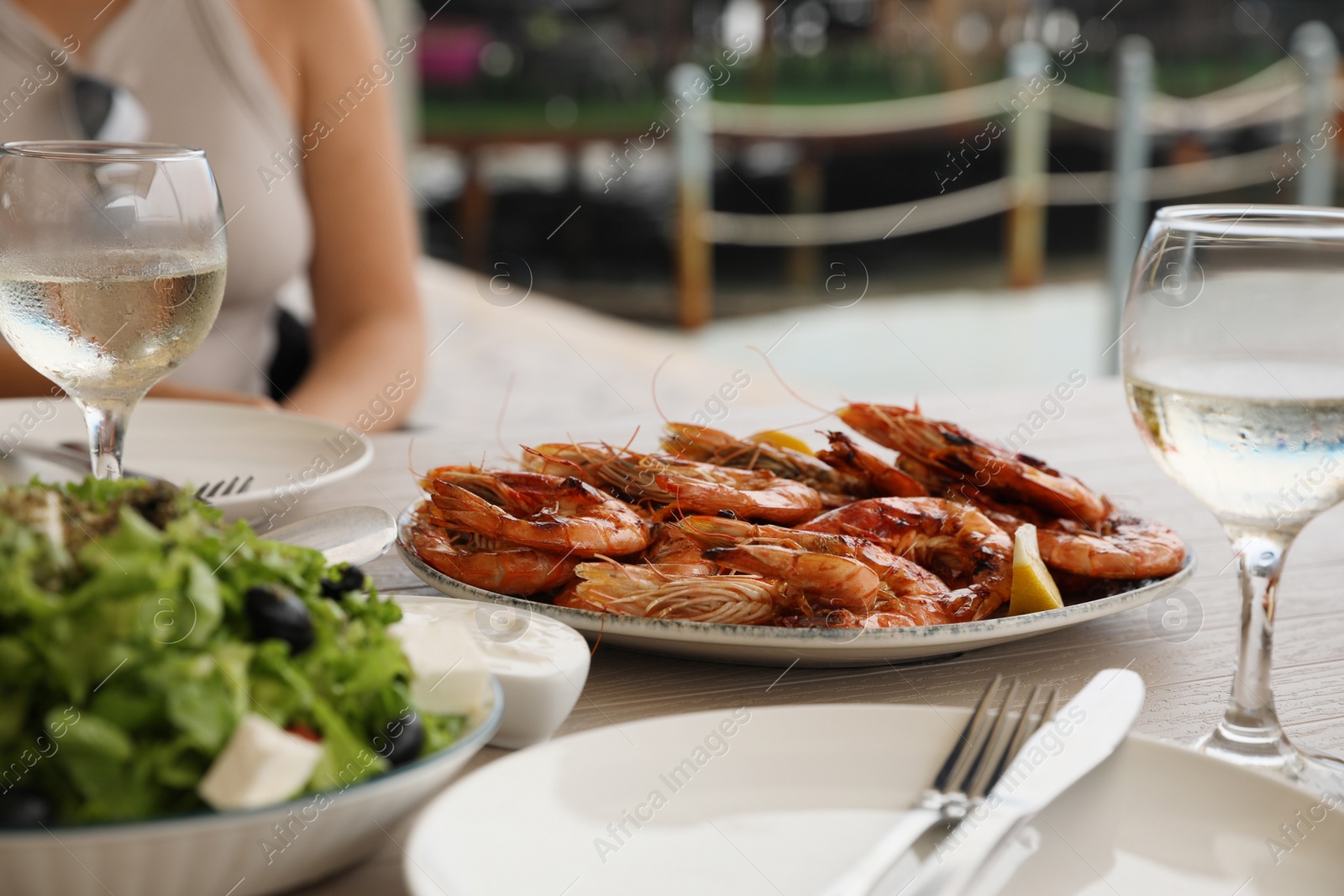 Photo of Plate of delicious cooked shrimps served with lemon and wine at table outdoors