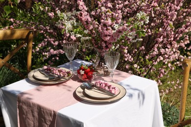 Photo of Stylish table setting with beautiful spring flowers in garden