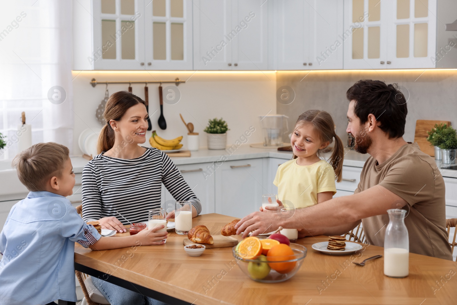 Photo of Happy family having breakfast at table in kitchen