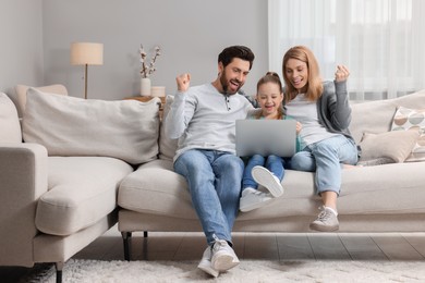 Photo of Emotional family with laptop on sofa at home