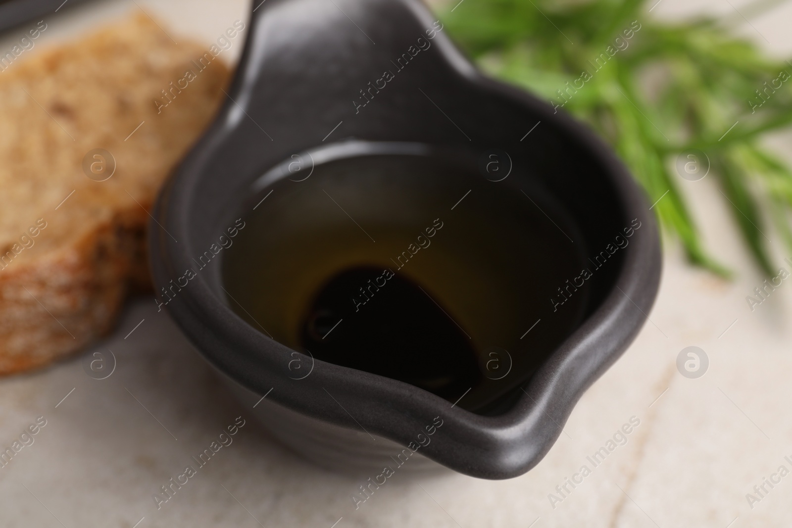 Photo of Saucepan of organic balsamic vinegar with oil on light grey table, closeup