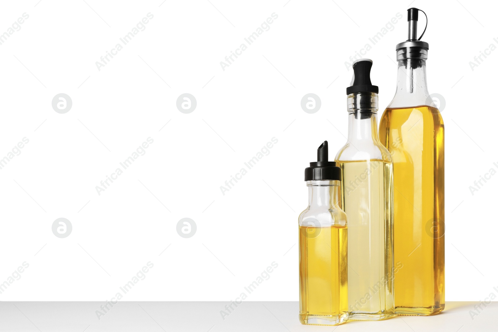 Photo of Bottles of different cooking oils on white background, space for text