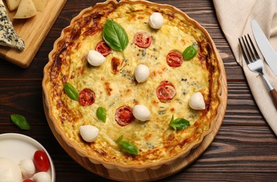 Photo of Delicious quiche with mozzarella cheese, tomatoes and basil on wooden table, flat lay