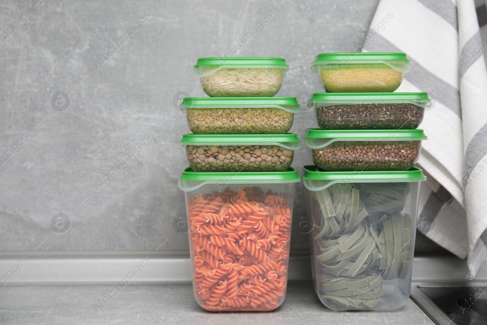 Photo of Plastic containers filled with food products on grey table. Space for text