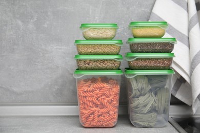 Photo of Plastic containers filled with food products on grey table. Space for text