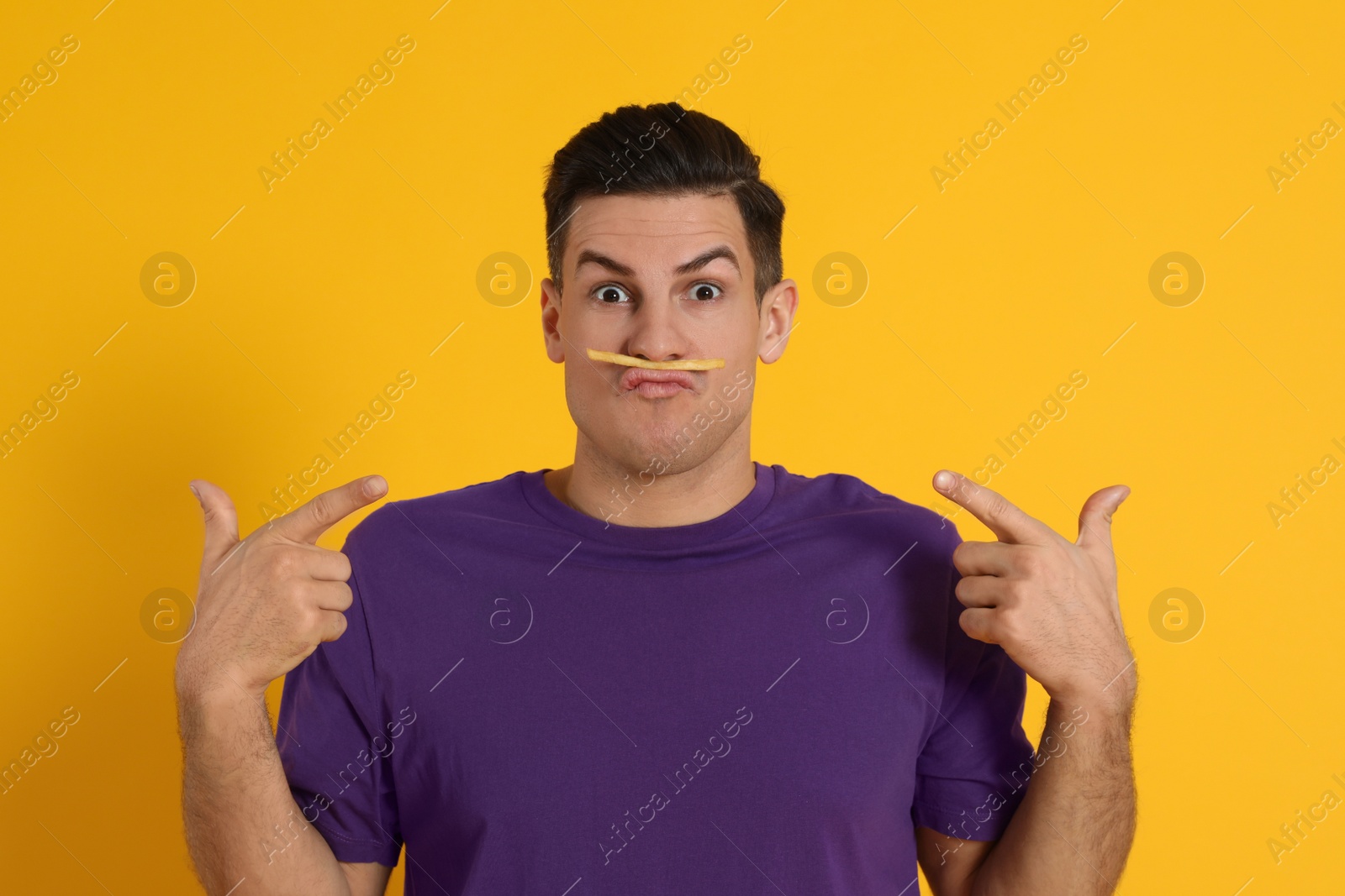 Photo of Man with French fries on orange background