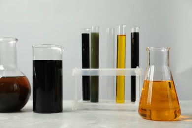 Photo of Laboratory glassware with different types of oil on white table