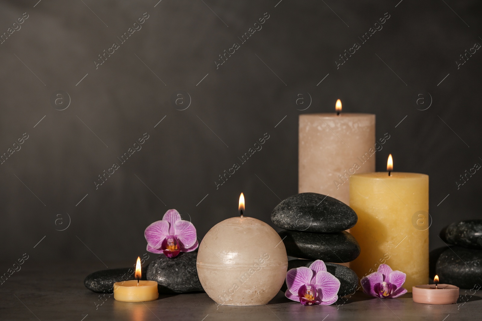 Photo of Composition with candles and spa stones on grey table. Space for text