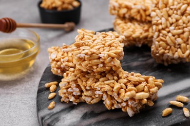 Photo of Board with puffed rice bars (kozinaki) on grey table, closeup