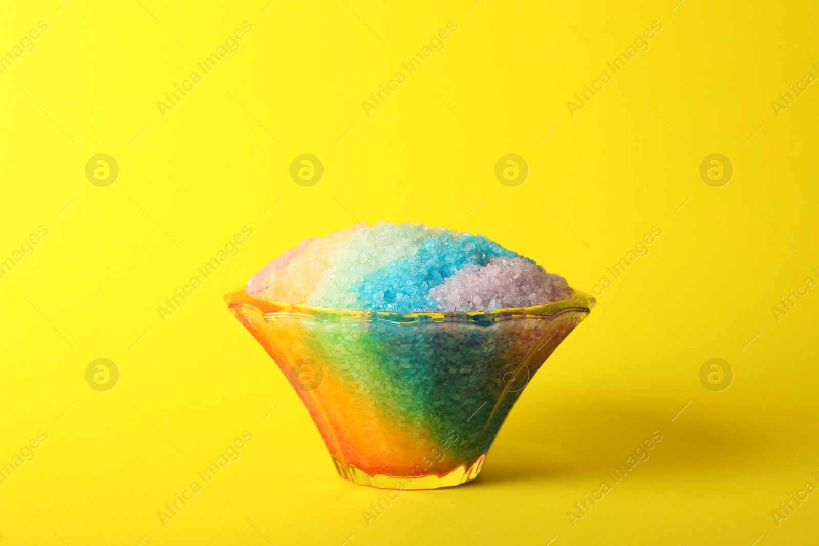 Photo of Rainbow shaving ice in glass dessert bowl on yellow background