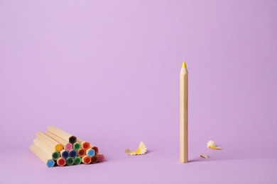 One pencil standing out from others on color background. Be different