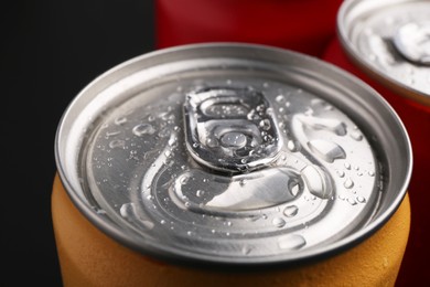 Photo of Energy drinks in wet cans on dark background, closeup