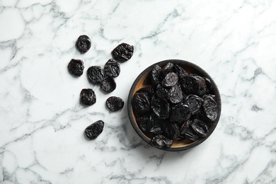Photo of Plate of sweet dried plums on marble background, top view. Healthy fruit